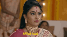 a woman with a nose ring and a necklace is wearing a pink and white saree .