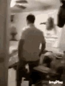 a man is standing in a room with a ceiling fan in the background .