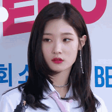 a woman wearing a white shirt and a pink tie is standing in front of a sign that says bf