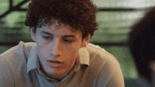 a young man with curly hair is looking at something