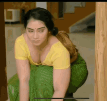 a woman in a yellow blouse and green pants is squatting down