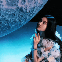 a woman in a floral dress is standing in front of a giant moon