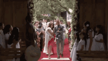 a bride and groom are walking down the aisle with their baby