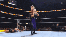 a woman in a wrestling ring is being lifted up by another woman in a purple outfit
