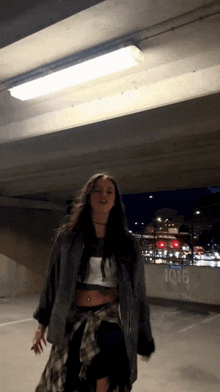 a woman is standing under a bridge with the number 1016 on the side