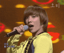 a young man singing into a microphone with a foreign language on the bottom right