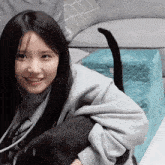 a girl in a grey sweatshirt holds a black cat in her arms