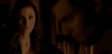 a woman is standing next to a man in a dark room .