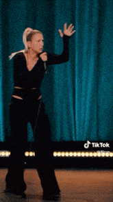 a woman singing into a microphone with a tiktok logo on the bottom right