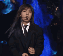 a woman with long hair is wearing a black suit and tie