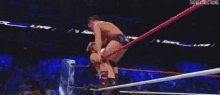 a wrestling match is taking place in front of a crowd .