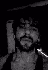 a man with a beard is sweating in a black tank top .