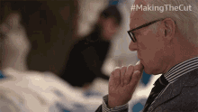 a man wearing glasses is sitting in front of a sign that says #making thecut