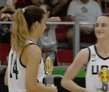 two female basketball players are standing next to each other on a court .
