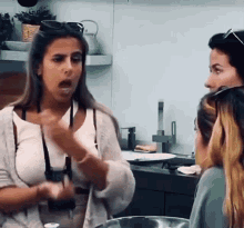 a woman with a camera around her neck is talking to two other women
