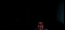 a young boy is smiling in the dark with a purple shirt on