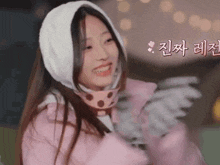a woman wearing a pink jacket and a white scarf smiles
