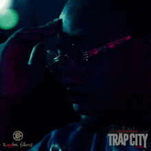 a movie poster for trap city shows a man talking on a cell phone