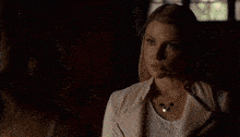 a woman in a white dress is standing in a dark room looking at something