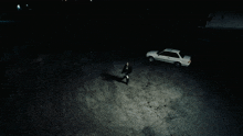 a man standing next to a white car in a dark parking lot