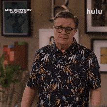 a man in a hawaiian shirt is standing in front of a sign that says mid century modern