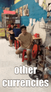a man sits on a red stool in a restaurant with other currencies written on the floor