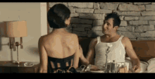 a man and a woman are sitting on a bed talking