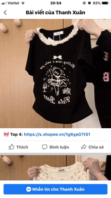a person is holding a black shirt with a teddy bear on it