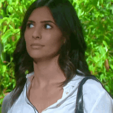 a woman wearing a white shirt and a black purse looks to the side