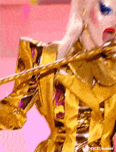 a woman in a gold and purple outfit is holding a violin