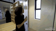 a woman stands in front of a mirror in a room with the words made in animatica on the bottom