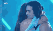 a man and a woman are hugging each other in a blue room .