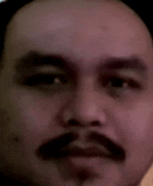 a man with a mustache is making a funny face .