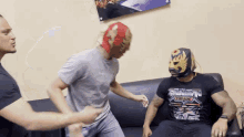 a man wearing a shirt that says scorpion titan is sitting on a couch