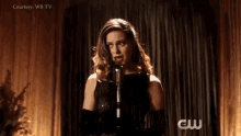 a woman in a black dress is singing into a microphone in a dark room .