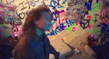 a woman is standing in front of a wall with graffiti on it including the word i love