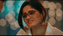 a woman wearing glasses and a white shirt smiles at the camera