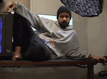 a man sitting on a desk with a sweatshirt that says athletics