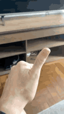 a close up of a person 's hand giving a thumbs up sign in front of a television .