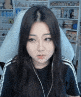 a woman wearing headphones is sitting in a chair in front of a shelf full of stuffed animals