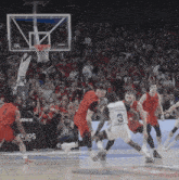 a basketball game is being played in front of a crowd that is cheering and watching