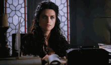 a woman with curly hair is sitting at a desk looking at something