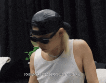 a man wearing a black hat and sunglasses has korean writing on the bottom right