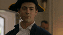 a man wearing a pirate hat looks at the camera with a serious look on his face