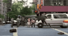 a group of people are walking down a city street while a car is driving down it .