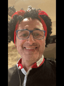 a man wearing glasses and a red headband looks at the camera