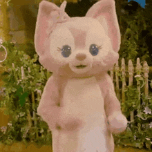 a stuffed animal is standing in front of a wooden fence in a garden .