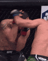 two men are fighting in a cage and one of them is wearing a pair of ufc shorts