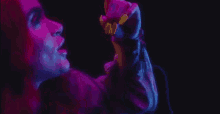 a close up of a woman singing into a microphone in a dark room with neon lights .