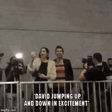 a man and a woman are jumping up and down in excitement while a cameraman takes a picture of them .